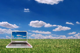 Computer setting on grass with beautiful blue sky and white clouds in background